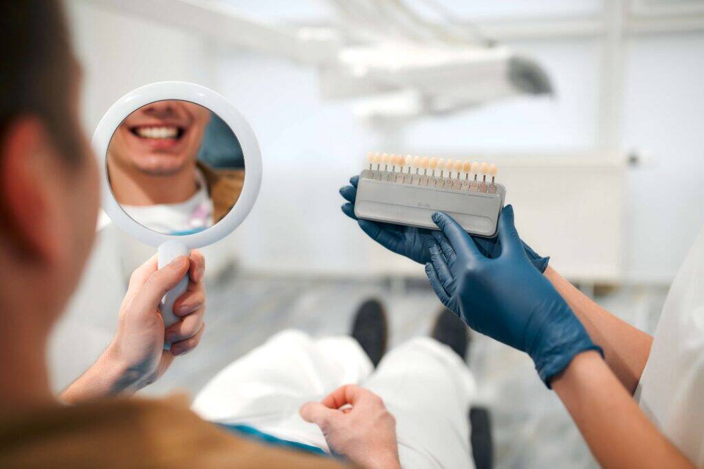Patient comparing smile shades with a dentist.